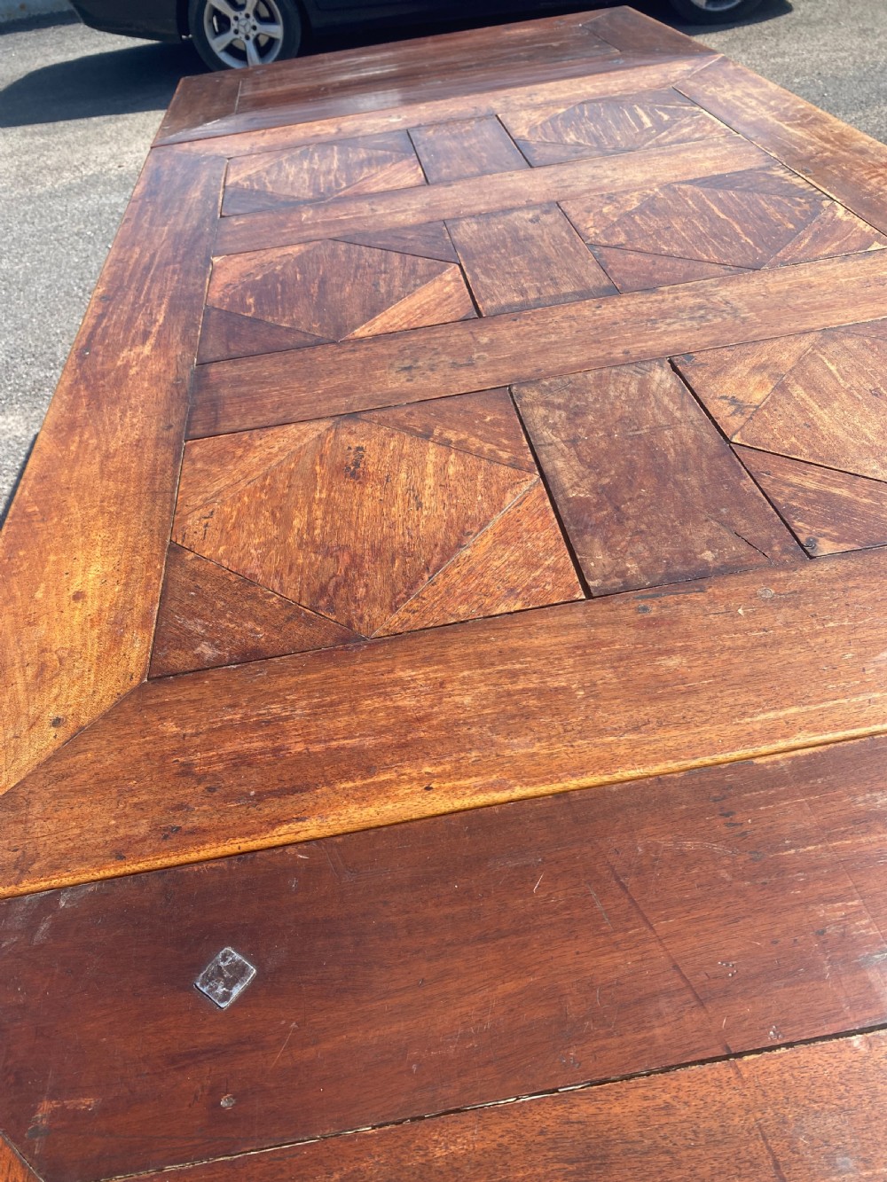 An 18th century Spanish fruitwood refectory dining table featuring a geometric parquet tabletop, draw-leaf extension panels, turned baluster legs, and a carved central stretcher. View III
