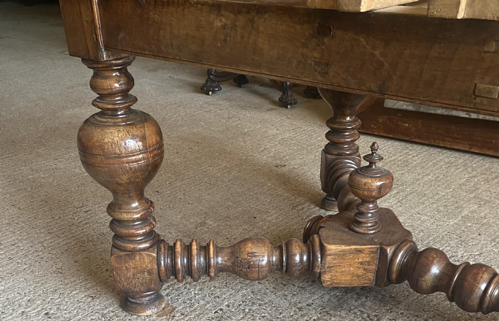 An 18th century Spanish fruitwood refectory dining table featuring a geometric parquet tabletop, draw-leaf extension panels, turned baluster legs, and a carved central stretcher. View VII