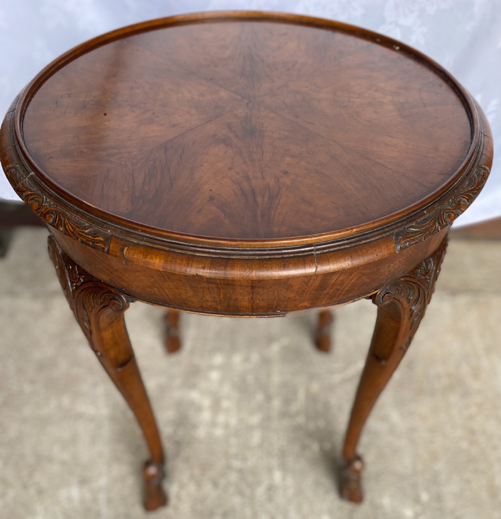 A circular antique walnut occasional table with quartered top veneer, carved apron details, and elegant cabriole legs ending in scroll feet. View II