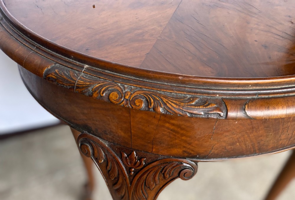 A circular antique walnut occasional table with quartered top veneer, carved apron details, and elegant cabriole legs ending in scroll feet. View III