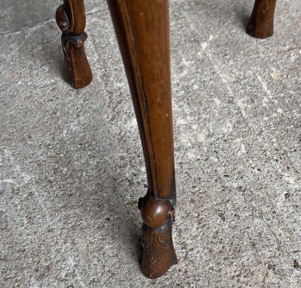 A circular antique walnut occasional table with quartered top veneer, carved apron details, and elegant cabriole legs ending in scroll feet. View IV