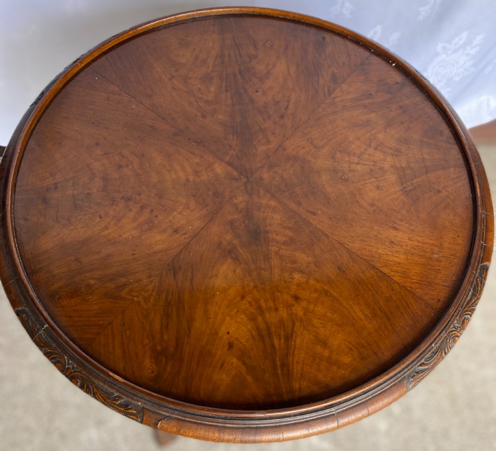 A circular antique walnut occasional table with quartered top veneer, carved apron details, and elegant cabriole legs ending in scroll feet. View V