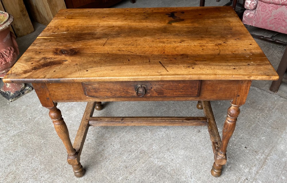 An 18th-century French fruitwood occasional table featuring a rectangular top, single drawer with an iron ring handle, turned legs, and a low stretcher base.