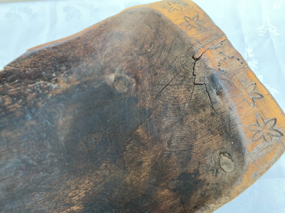 A long hand-carved dark wood bowl featuring incised star motifs on the raised rim handles and a hollowed interior. View II