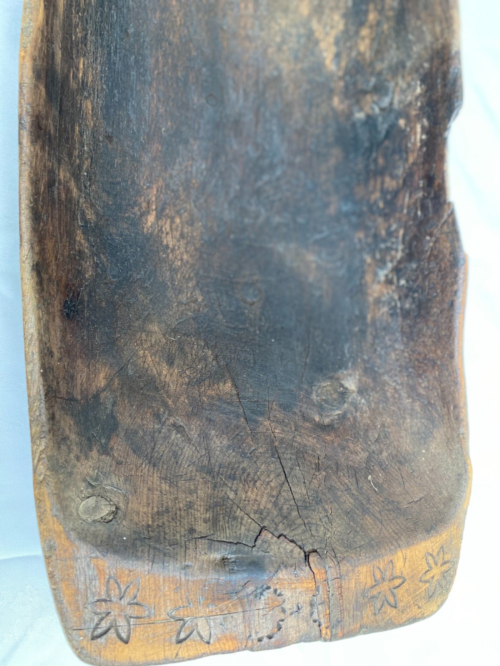 A long hand-carved dark wood bowl featuring incised star motifs on the raised rim handles and a hollowed interior. View III