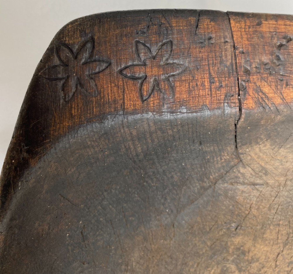 A long hand-carved dark wood bowl featuring incised star motifs on the raised rim handles and a hollowed interior. View IV
