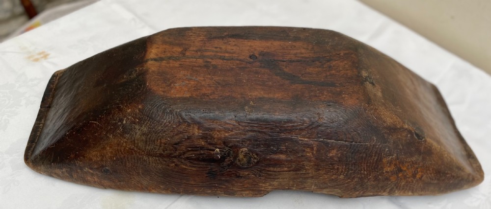 A long hand-carved dark wood bowl featuring incised star motifs on the raised rim handles and a hollowed interior. View VI
