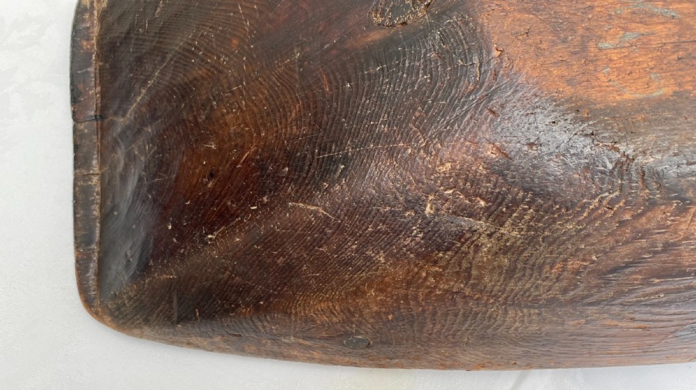 A long hand-carved dark wood bowl featuring incised star motifs on the raised rim handles and a hollowed interior. View VII