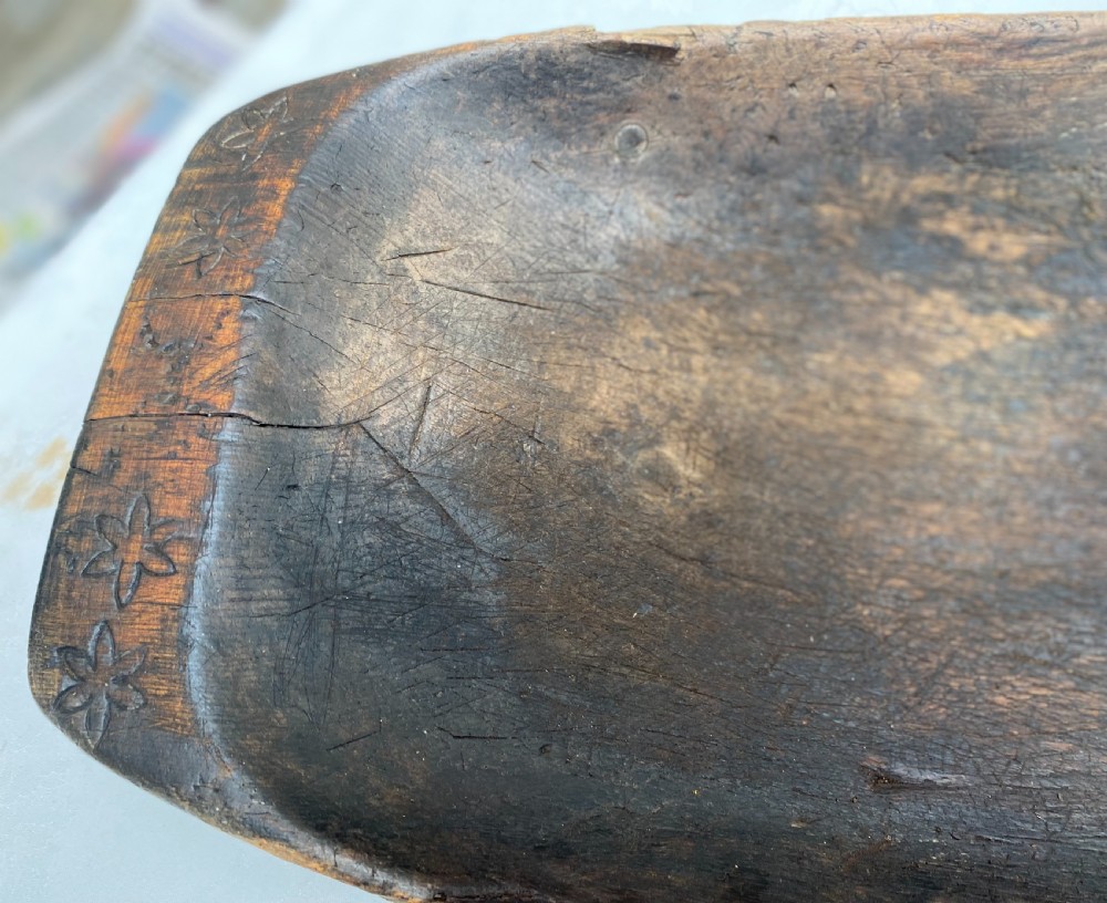 A long hand-carved dark wood bowl featuring incised star motifs on the raised rim handles and a hollowed interior. View IX