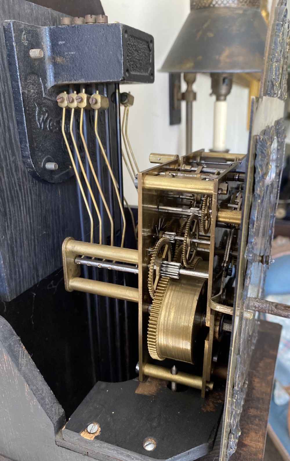 A dark oak Jacobean style grandmother clock featuring barley twist columns, geometric door panel mouldings, an arched hood, and an ornate brass dial. View VII