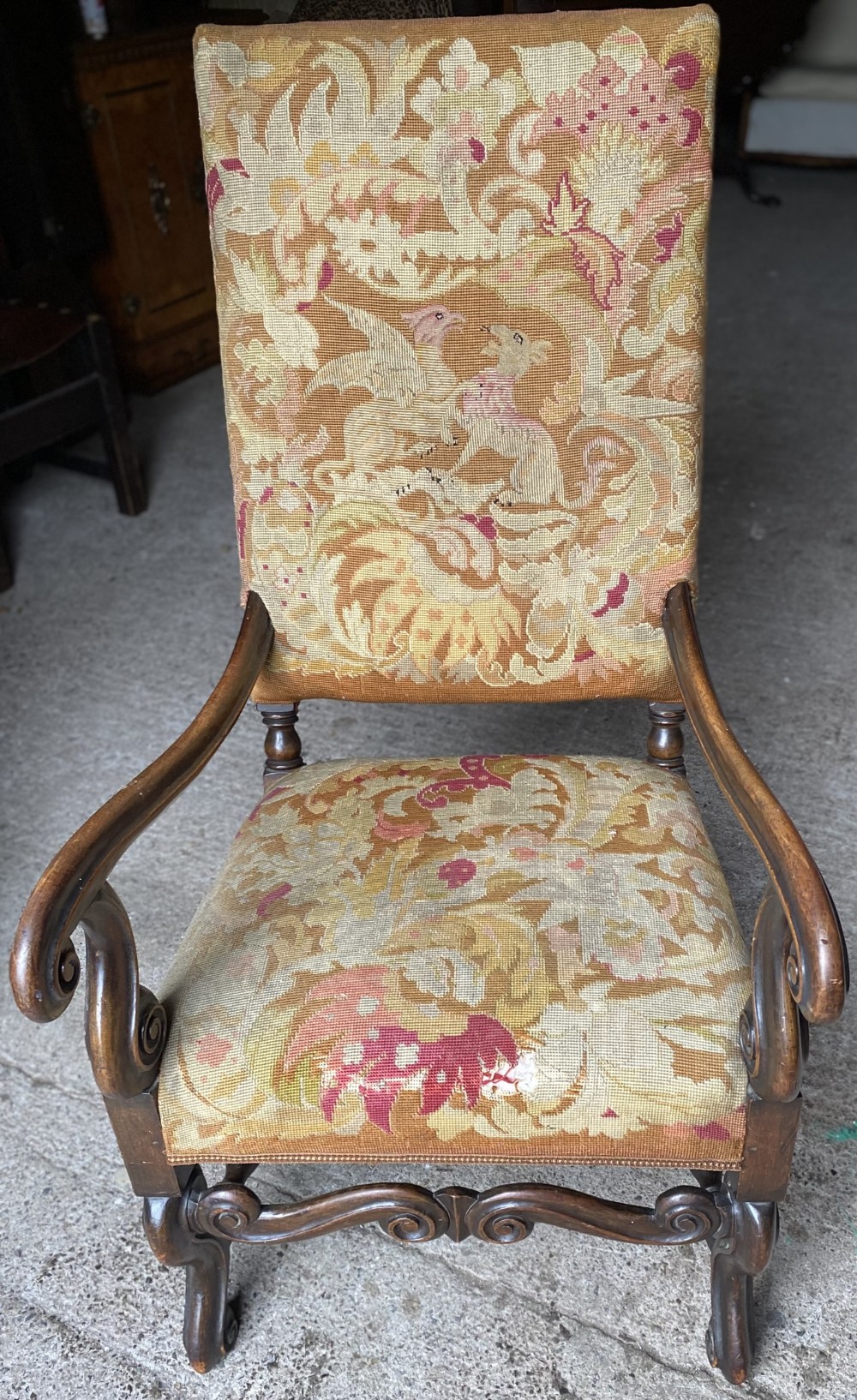 A 19th-century French open armchair crafted from carved walnut timber, featuring scroll arms and tapestry upholstery with floral and mythical animal patterns.