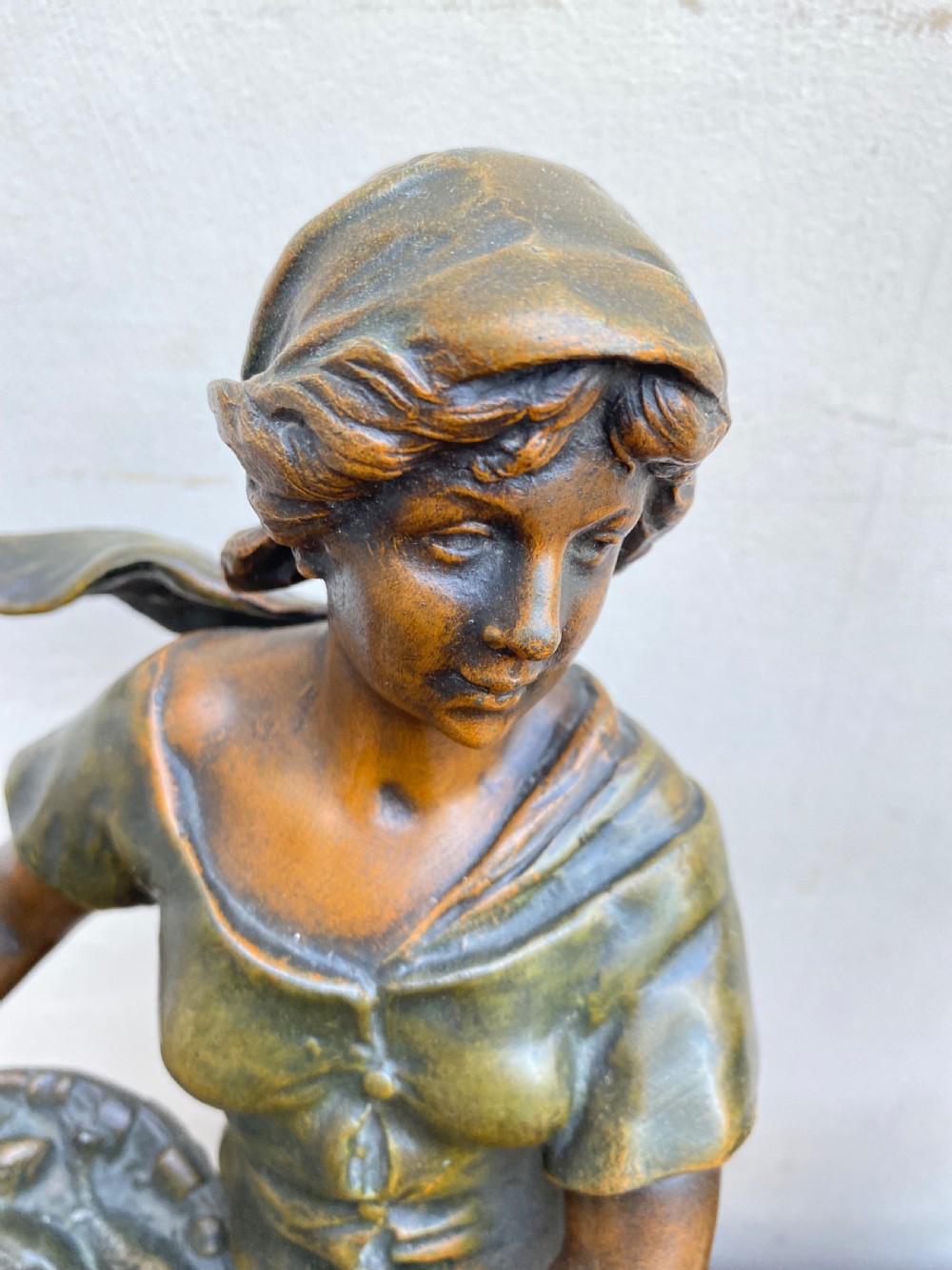 A pair of patinated spelter figures depicting a fisherwoman holding a basket and a fisherman carrying nets, mounted on circular turned wood bases with brass title plates. View VI