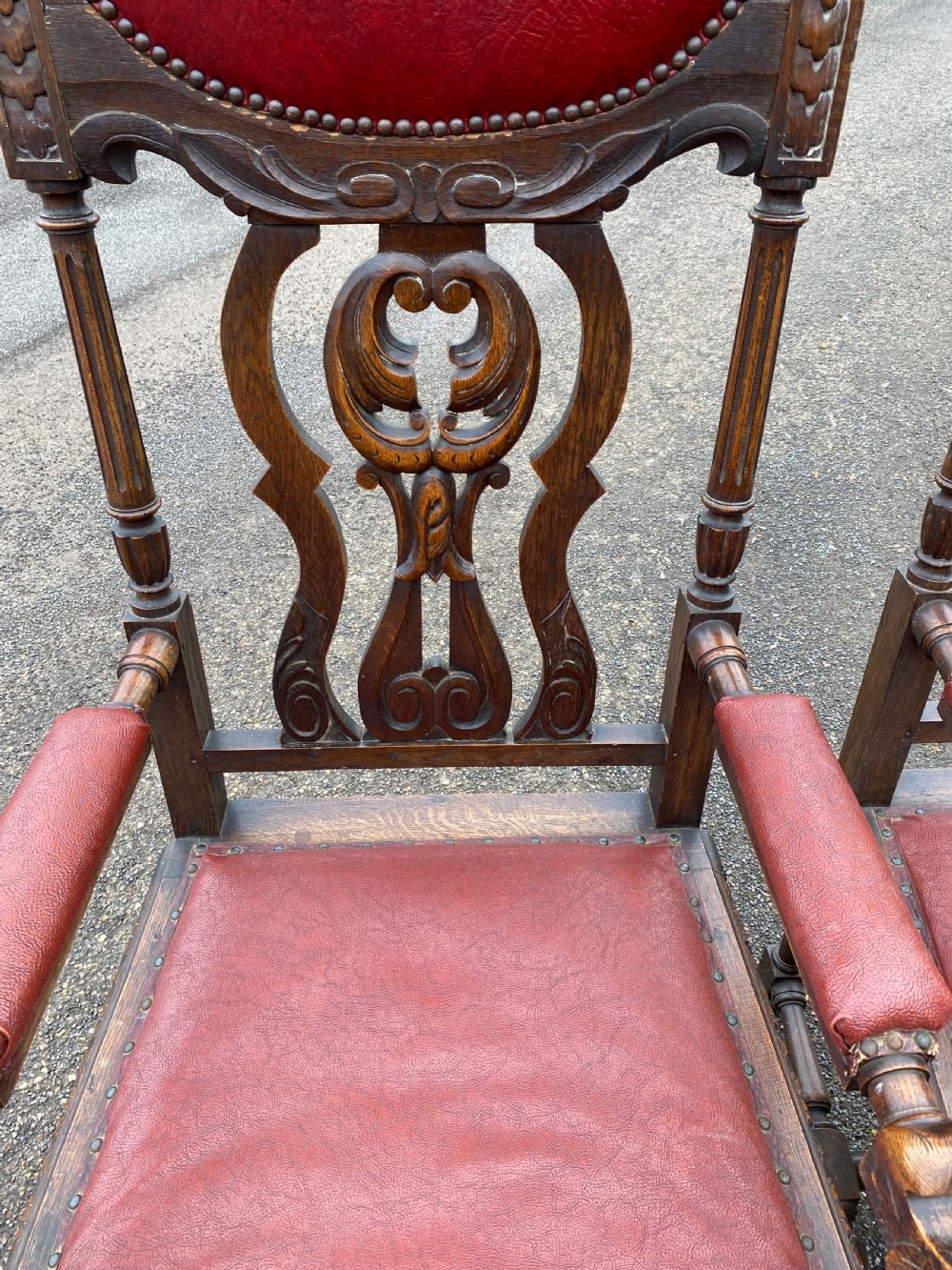 A pair of high-backed carved dark oak armchairs featuring red upholstered seats and matching oval back cushions. View II
