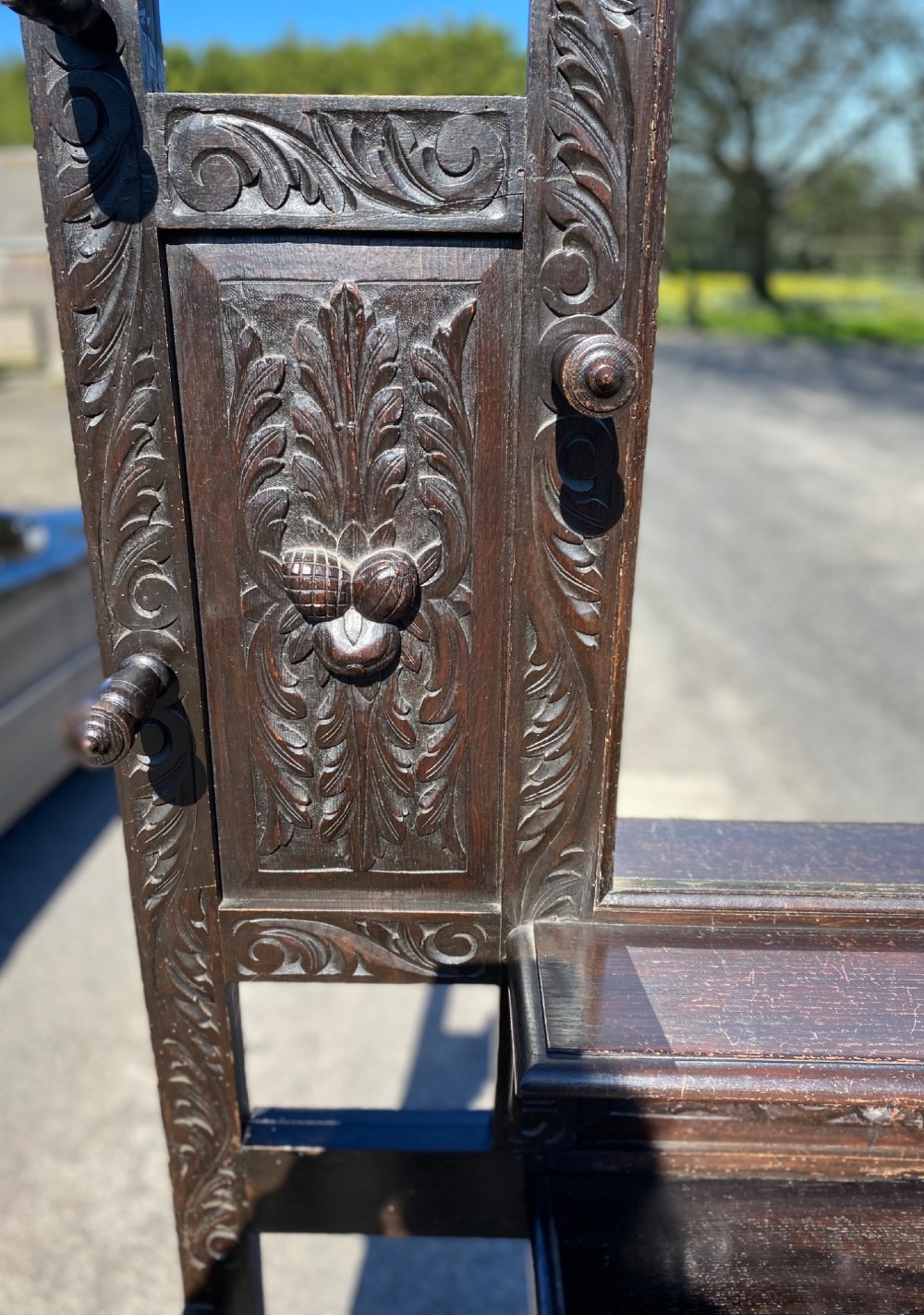 A dark carved oak Victorian hall stand featuring a central rectangular mirror, lion mask carvings, turned coat pegs, umbrella holders, and metal drip trays. View IV