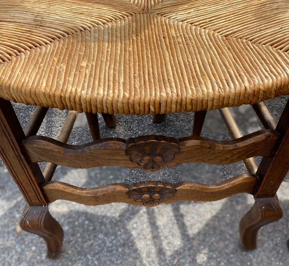 A set of French carved cedarwood dining chairs featuring ladderbacks with shell motifs and natural woven rush seats. View IV