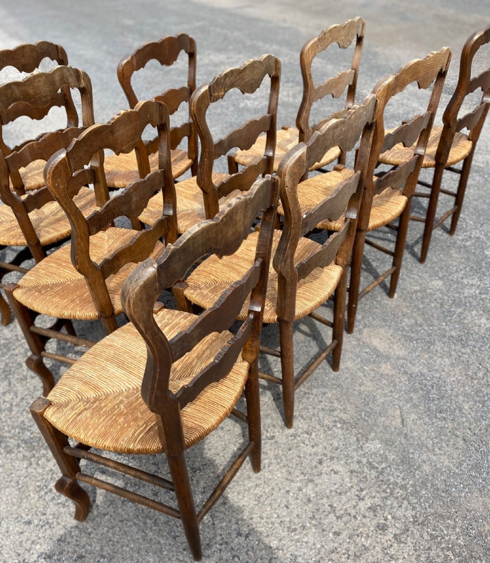 A set of French carved cedarwood dining chairs featuring ladderbacks with shell motifs and natural woven rush seats. View VI