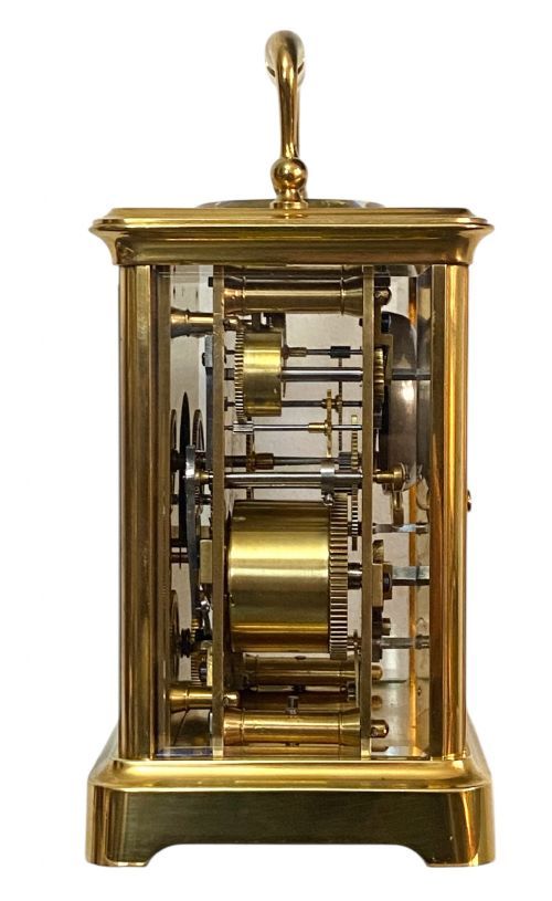 fig 1. A rectangular gilt brass carriage clock featuring a folding top handle, white enamel dial with Roman numerals, and a lower auxiliary alarm dial.