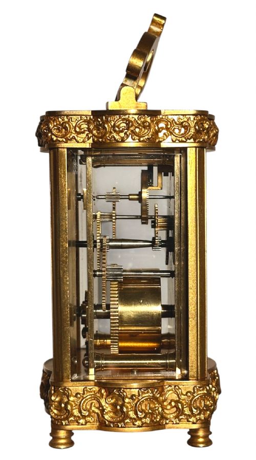 fig 1. A French gilded brass carriage clock featuring an ornate top handle, detailed relief scrollwork borders, and a porcelain dial decorated with an equestrian scene.