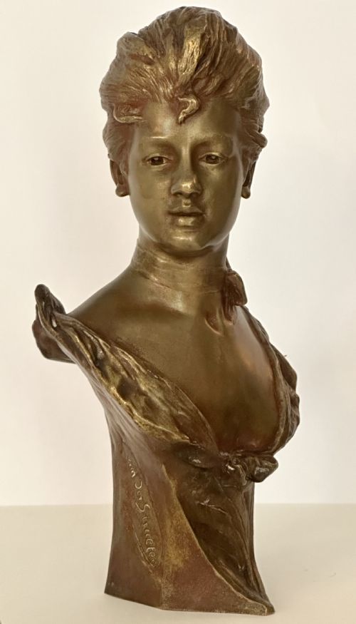 fig 1. An Art Nouveau patinated bronze bust depicting a young woman with swept-back hair, wearing a high-collared dress, signed Van Der Straeten.