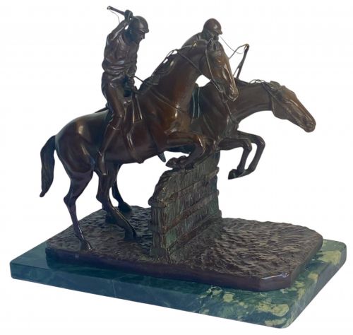 fig 1. A dark brown bronze sculpture depicting two racehorses and jockeys clearing a fence during a steeplechase, mounted on a polished green marble base.