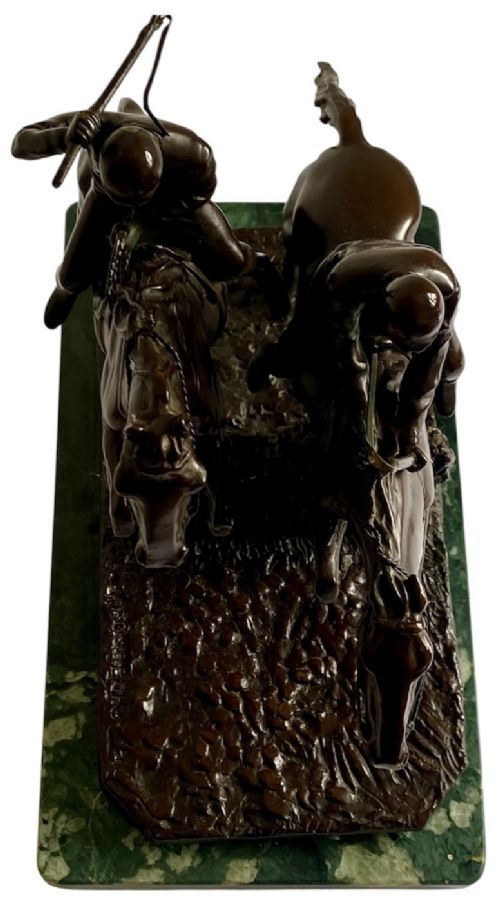 A dark brown bronze sculpture depicting two racehorses and jockeys clearing a fence during a steeplechase, mounted on a polished green marble base. View X