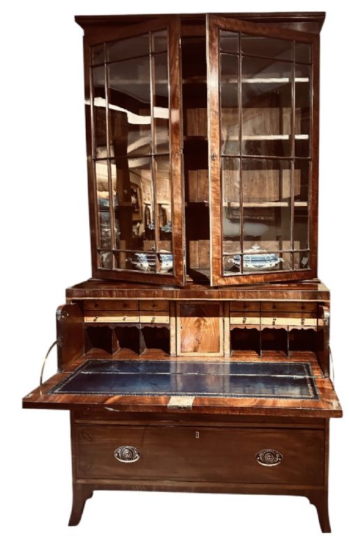fig 1. An antique Regency mahogany secretaire bookcase featuring an upper two-door glazed cabinet above a lower chest of drawers with decorative inlay and brass oval drop handles.