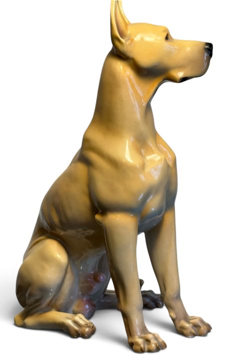 fig 1. A glazed fawn-coloured Nymphenburg porcelain figurine depicting a seated Great Dane with erect ears and a black muzzle.