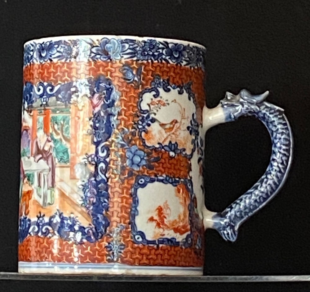 An 18th-century cylindrical Chinese export porcelain tankard decorated with Mandarin figures, panels of birds, iron-red lattice background, and a sculpted blue dragon handle.