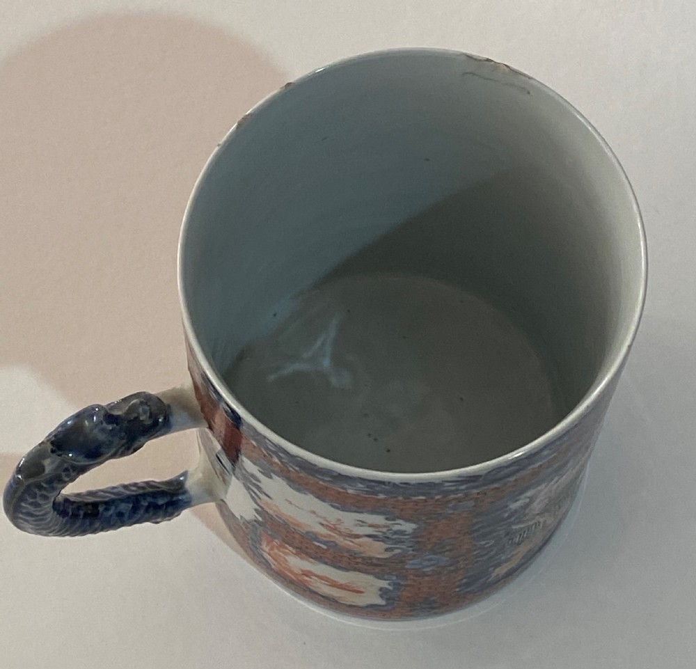 An 18th-century cylindrical Chinese export porcelain tankard decorated with Mandarin figures, panels of birds, iron-red lattice background, and a sculpted blue dragon handle. View V