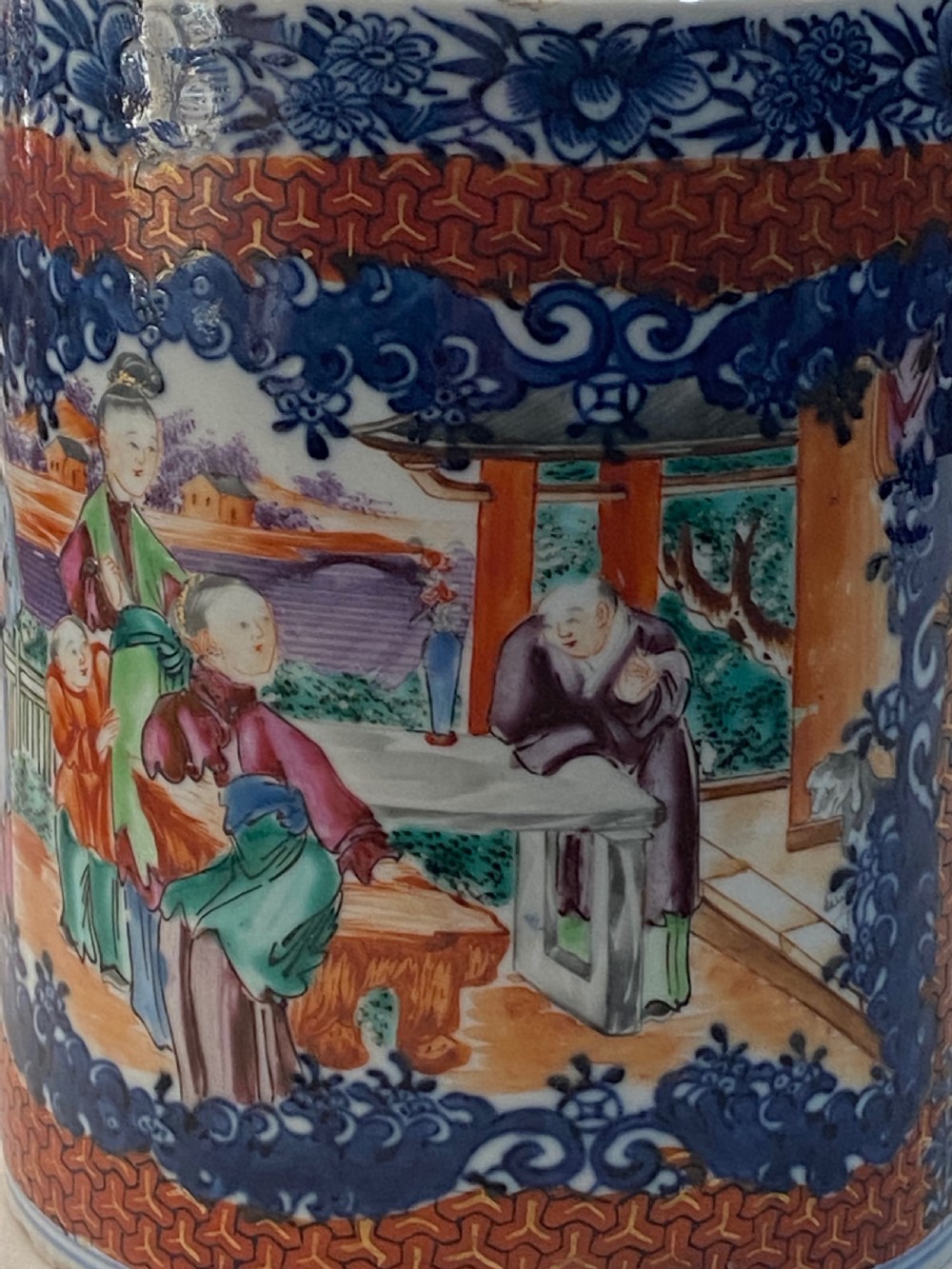 An 18th-century cylindrical Chinese export porcelain tankard decorated with Mandarin figures, panels of birds, iron-red lattice background, and a sculpted blue dragon handle. View IX