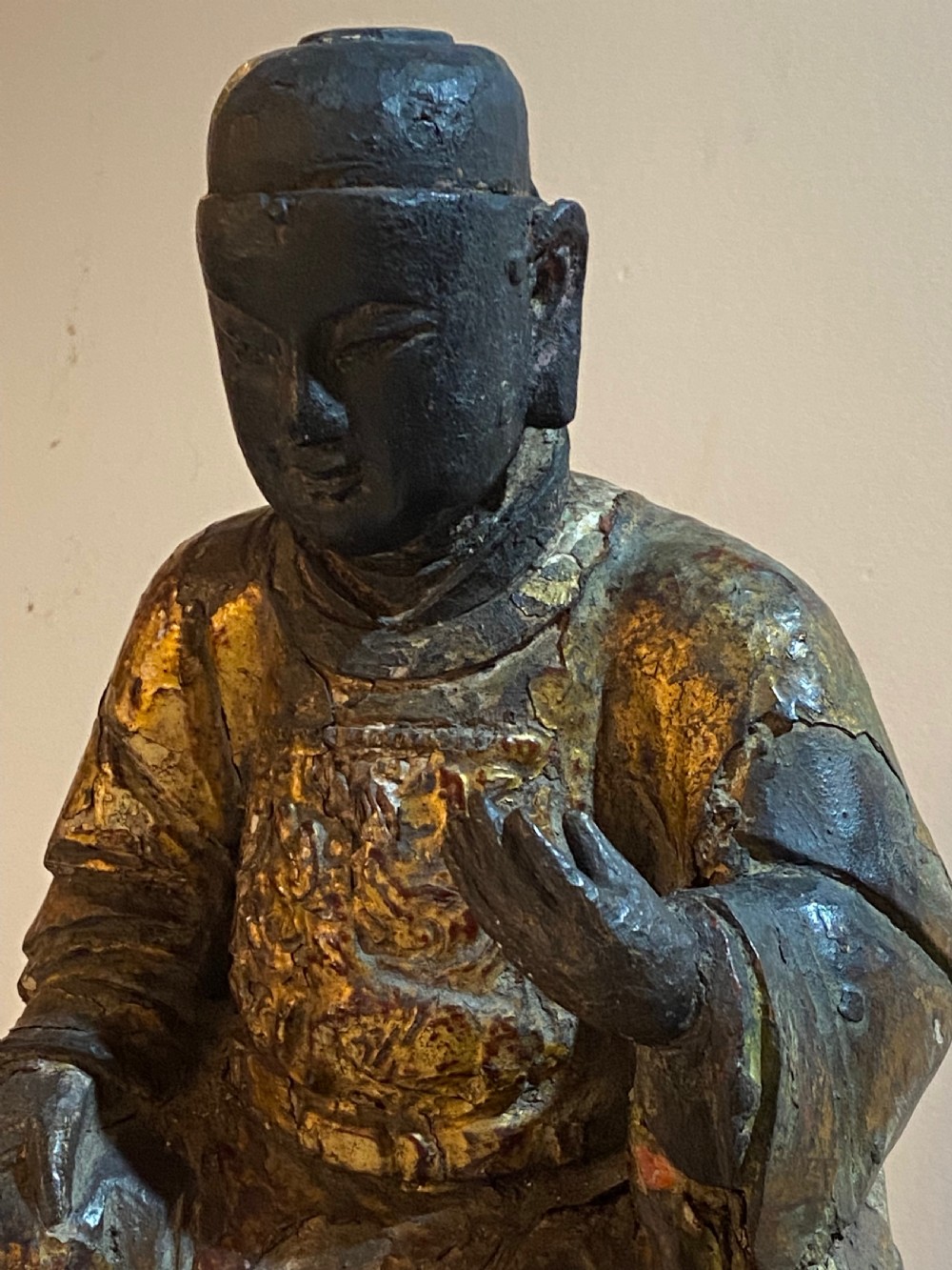 An eighteenth-century hand-carved wooden Chinese deity statue featuring worn gold leaf gilding and dark lacquer finish in a seated pose. View III