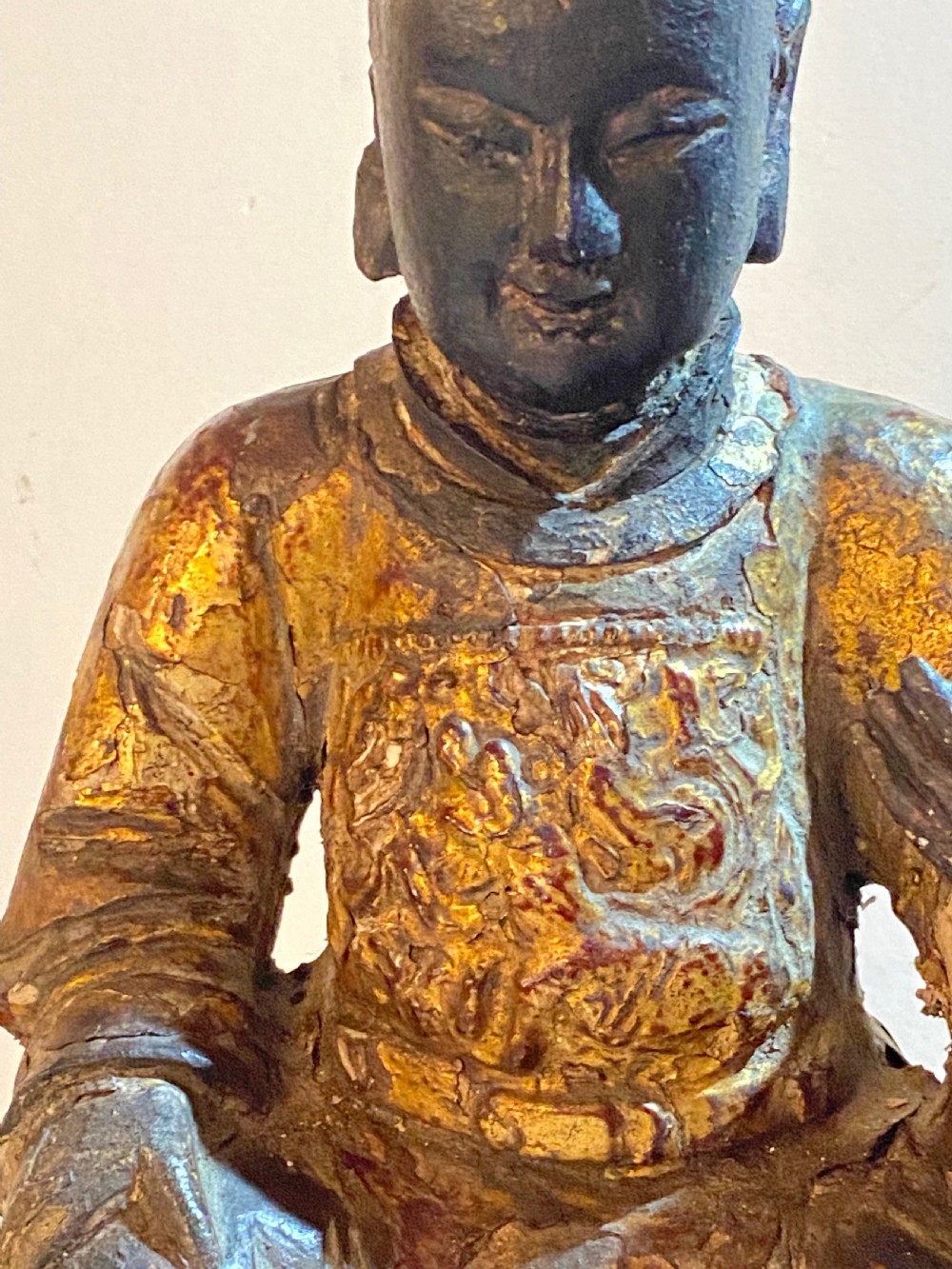 An eighteenth-century hand-carved wooden Chinese deity statue featuring worn gold leaf gilding and dark lacquer finish in a seated pose. View IV