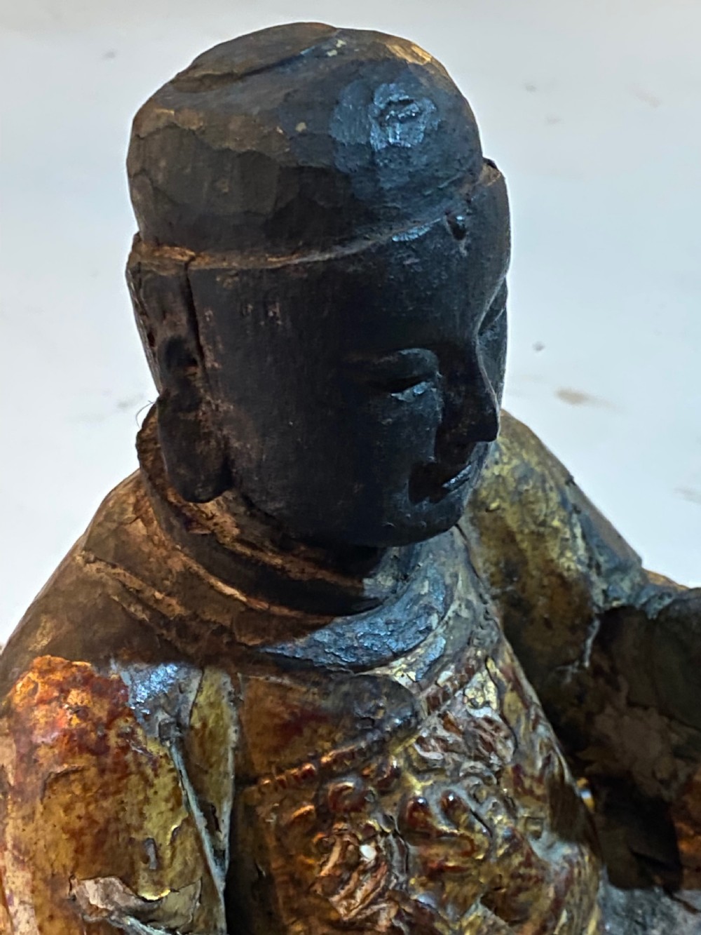 An eighteenth-century hand-carved wooden Chinese deity statue featuring worn gold leaf gilding and dark lacquer finish in a seated pose. View XII