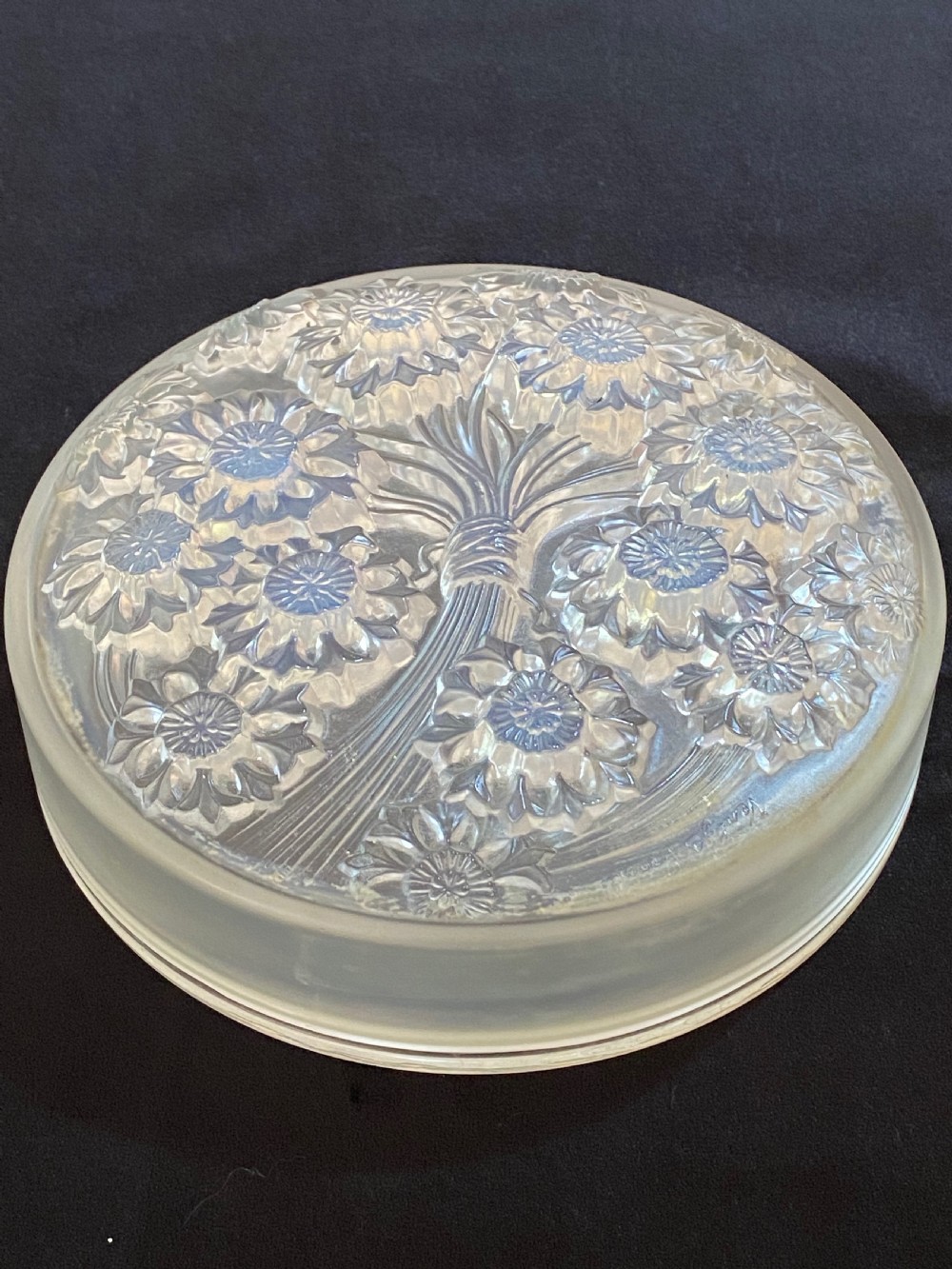 A circular French Art Deco opalescent glass box and cover with a raised moulded floral motif.