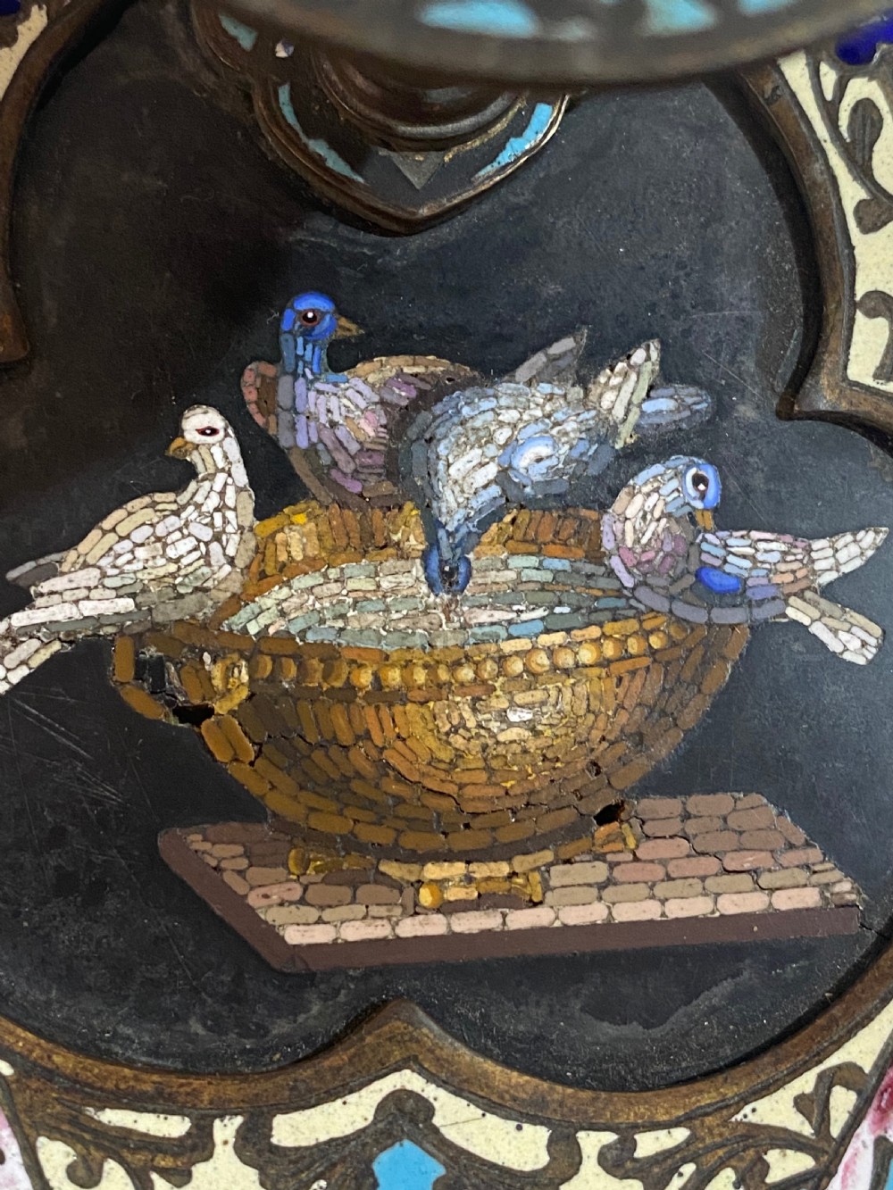 An antique metal chamberstick decorated with turquoise cloisonne enamel scrollwork surrounding a central micromosaic panel of birds drinking from a bowl. View X