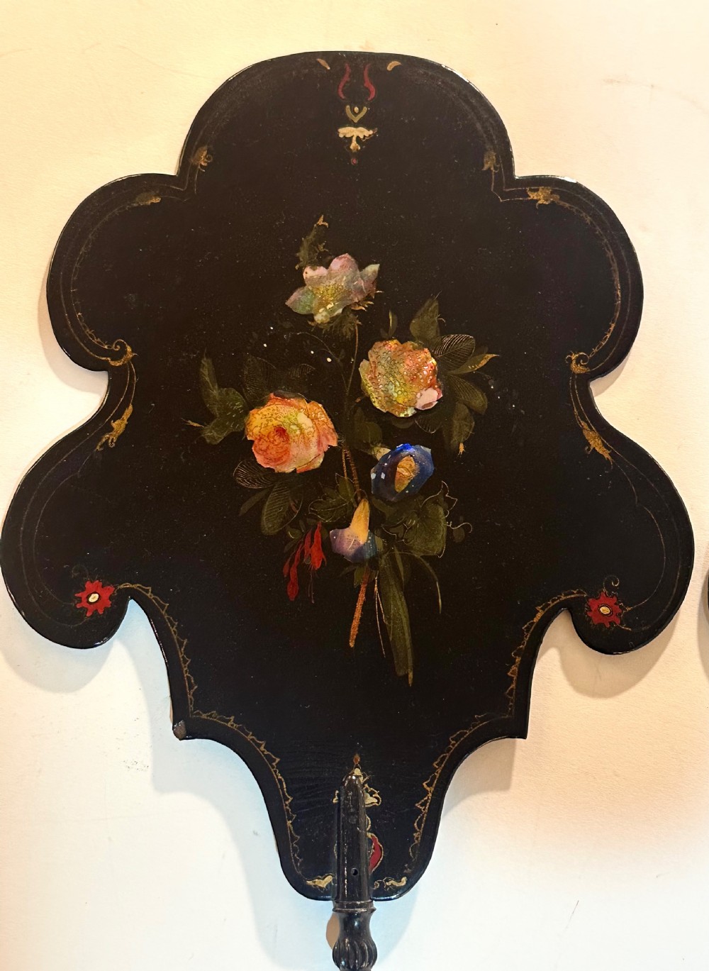 A pair of black Victorian papier-mache face screens with scalloped edges, hand-painted floral motifs inlaid with mother-of-pearl, and turned ebonised handles. View II
