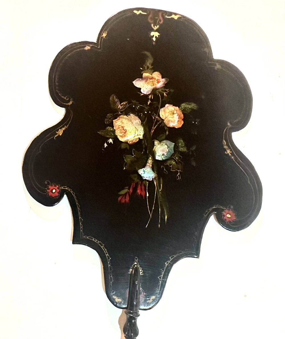 A pair of black Victorian papier-mache face screens with scalloped edges, hand-painted floral motifs inlaid with mother-of-pearl, and turned ebonised handles. View X