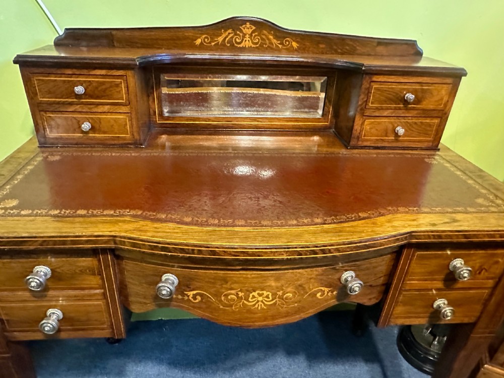 An Edwardian rosewood writing desk with satinwood marquetry, a dark brown leather writing surface, a raised superstructure with small drawers and a mirror, standing on tapered legs with castors. View III