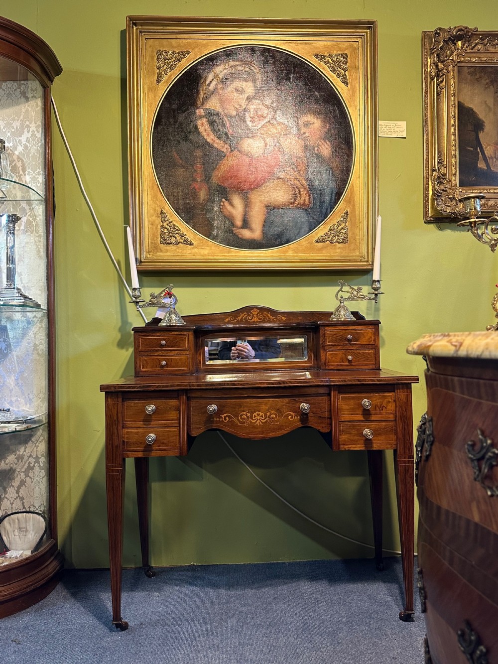 An Edwardian rosewood writing desk with satinwood marquetry, a dark brown leather writing surface, a raised superstructure with small drawers and a mirror, standing on tapered legs with castors. View X