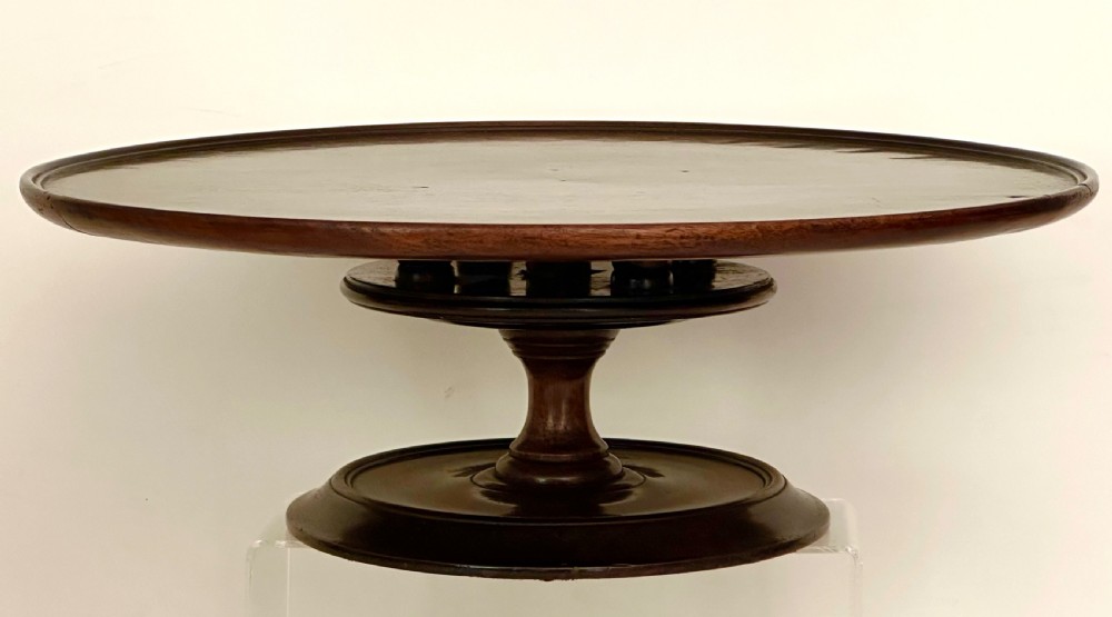 A circular Georgian mahogany Lazy Susan with a raised lip edge set upon a turned pedestal stem and wide circular base.