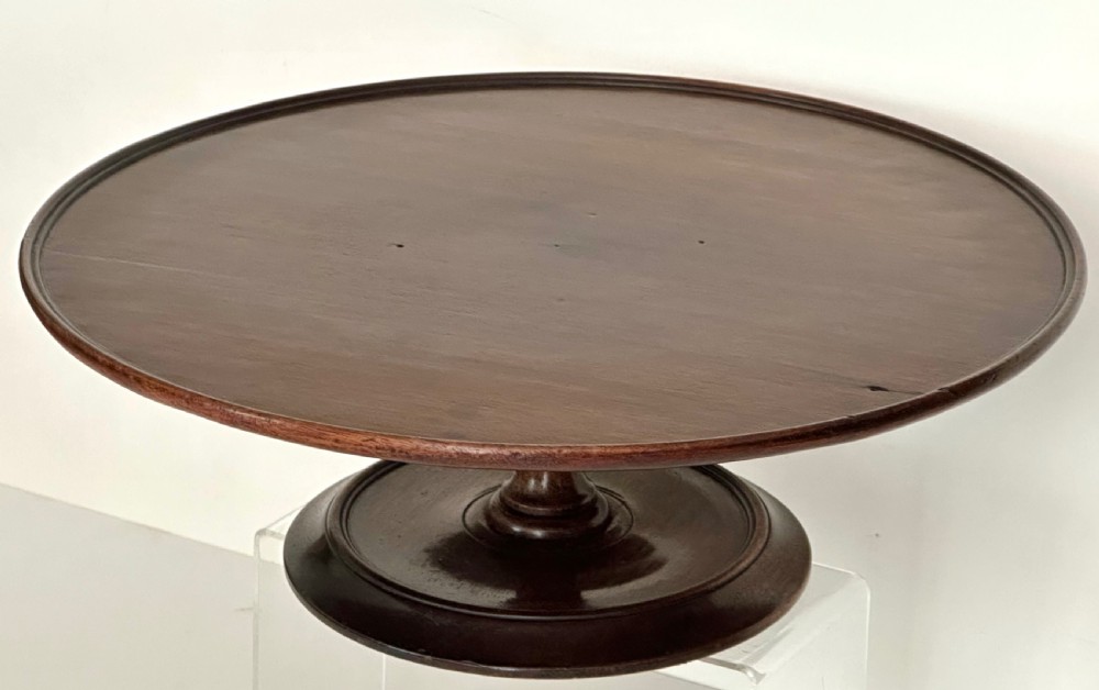 A circular Georgian mahogany Lazy Susan with a raised lip edge set upon a turned pedestal stem and wide circular base. View II
