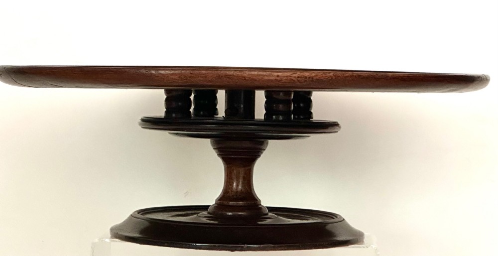 A circular Georgian mahogany Lazy Susan with a raised lip edge set upon a turned pedestal stem and wide circular base. View III