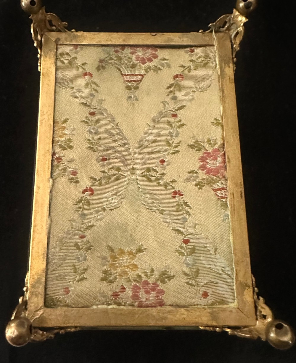 A rectangular French glass trinket box featuring a gilded ormolu frame, bevelled glass panels, decorative cast feet, and a tufted tan velvet cushion inside. View X