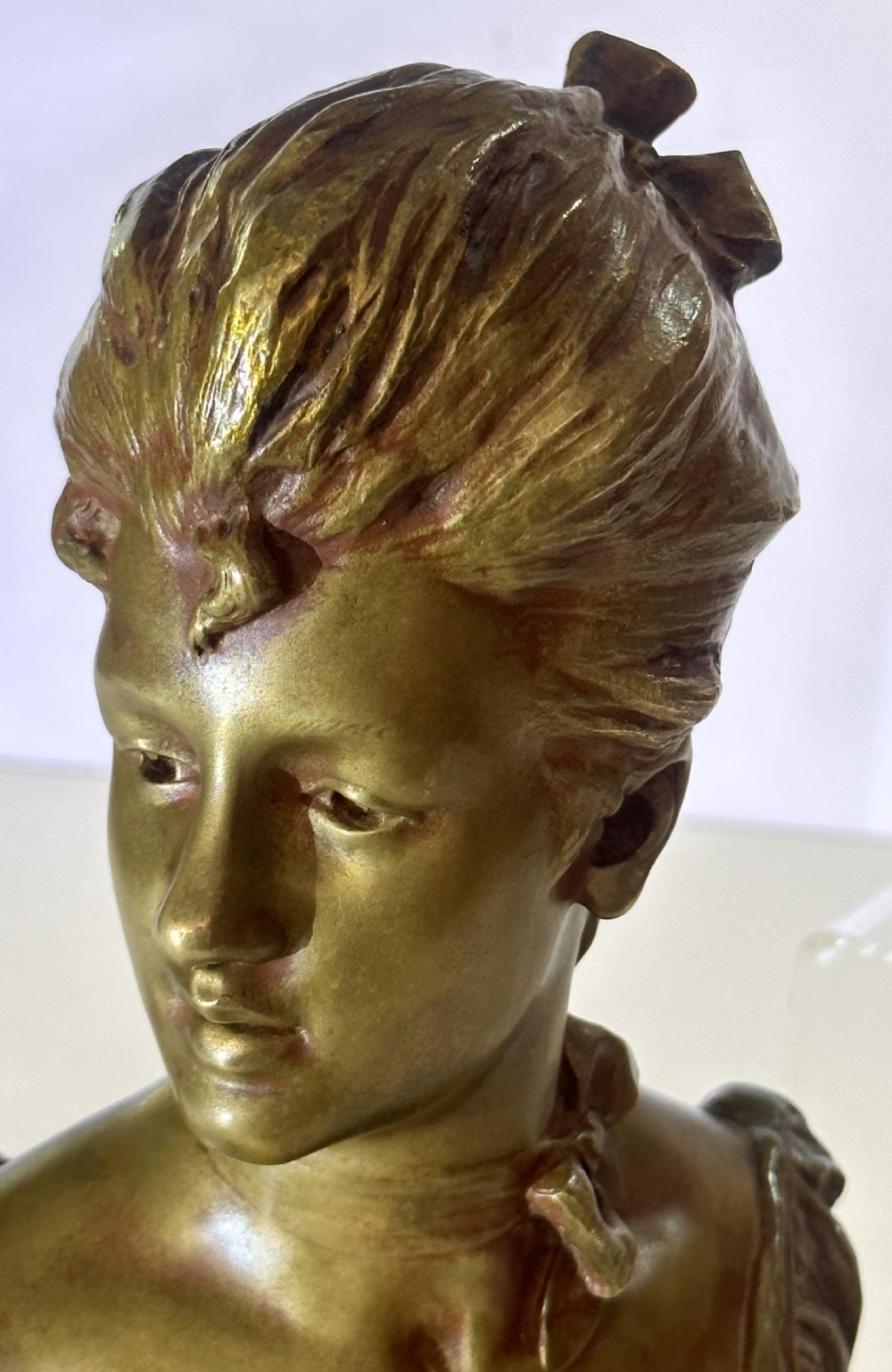 An Art Nouveau patinated bronze bust depicting a young woman with swept-back hair, wearing a high-collared dress, signed Van Der Straeten. View VI