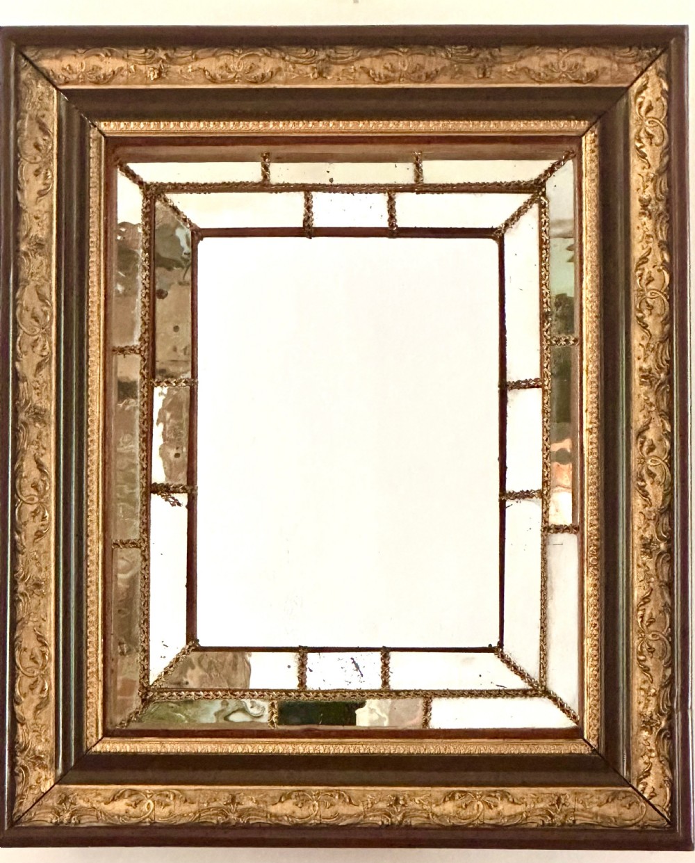 A rectangular nineteenth-century Italian wall mirror featuring a moulded dark wood and gilded carved frame surrounding marginal mirrored glass panels.