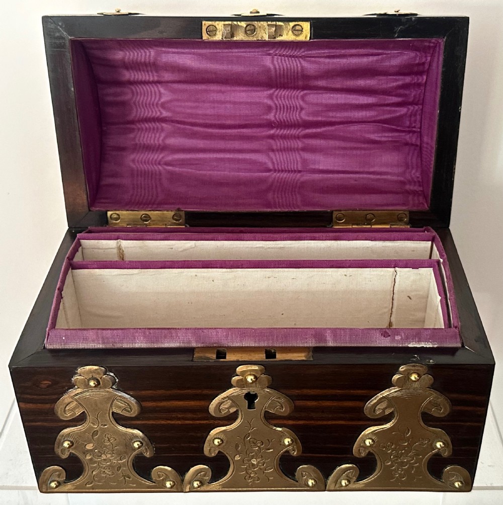 A dark coromandel wood stationery box featuring a domed lid decorated with engraved brass strapwork mounts and a central keyhole. View V