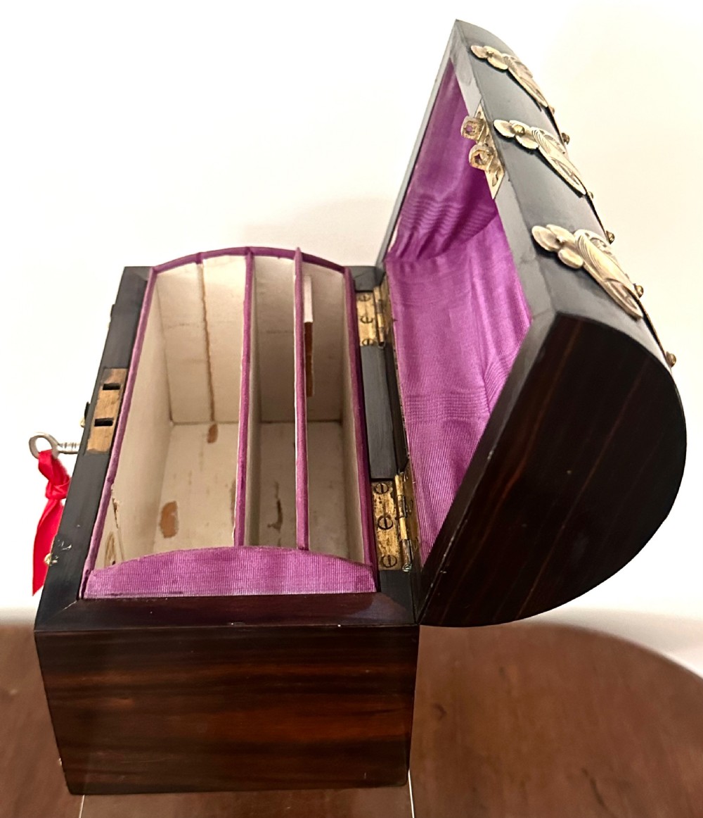 A dark coromandel wood stationery box featuring a domed lid decorated with engraved brass strapwork mounts and a central keyhole. View VI