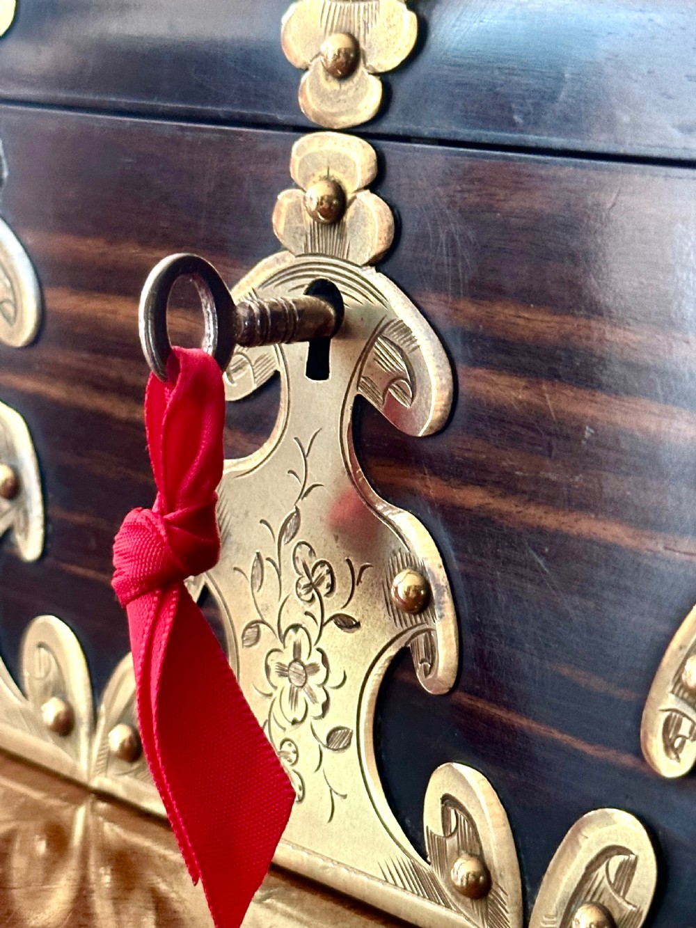A dark coromandel wood stationery box featuring a domed lid decorated with engraved brass strapwork mounts and a central keyhole. View IX