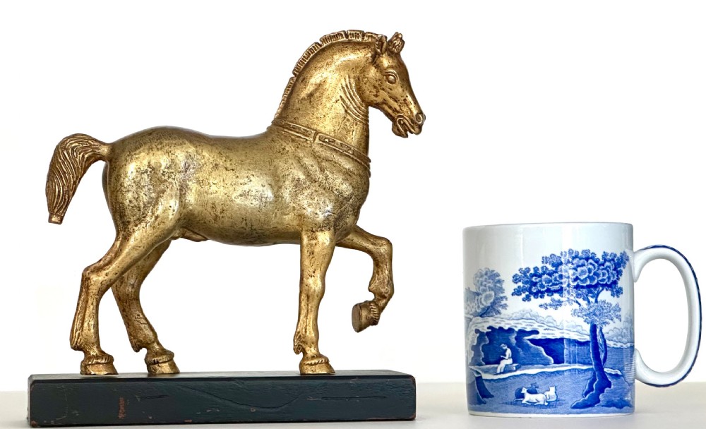 A gilded bronze horse sculpture in a striding pose with one raised hoof, mounted on a dark rectangular base. View II