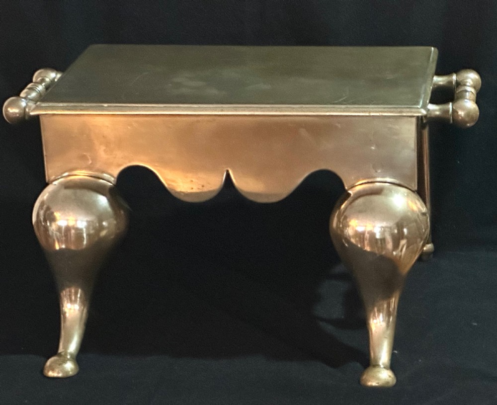 A Georgian brass fireplace footman featuring a rectangular top, shaped front apron, turned side handles, and cabriole front legs. View IV